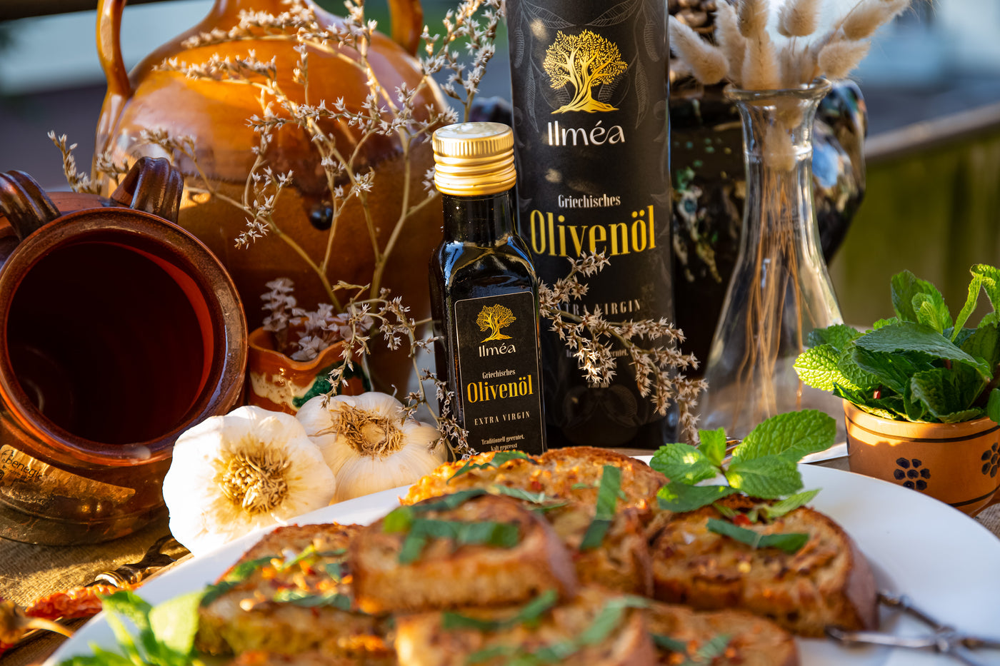 Ilmea Olivenöl Flasche 100ml mit Knoblauchbrot neben einer Grossen 750ml Olivenöl-Flasche